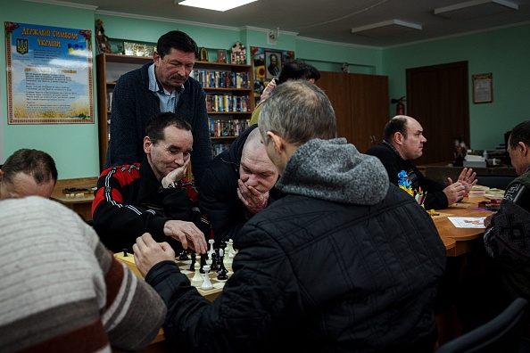 -Le directeur de l'hôpital, regarde des patients jouant aux échecs dans le centre résidentiel psycho-neurologique pour hommes dans la périphérie ouest de Kiev, le 12 mars 2022. Photo de Dimitar DILKOFF/AFP via Getty Images.