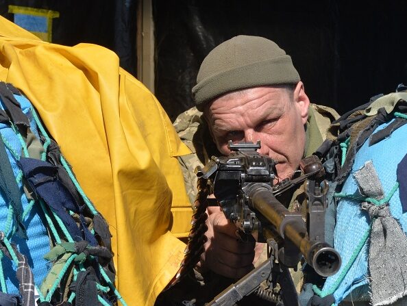 Un militaire ukrainien pointe son arme alors qu'il monte la garde à un poste de contrôle militaire à Kharkiv le 22 mars 2022. Photo de Sergey BOBOK / AFP via Getty Images.