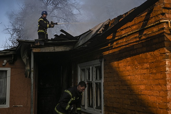 -Les pompiers éteignent une maison en feu touchée par des roquettes russes dans le district Shevchenkivsky de Kiev, le 22 mars 2022. Photo par Aris MESSINIS/AFP via Getty Images.