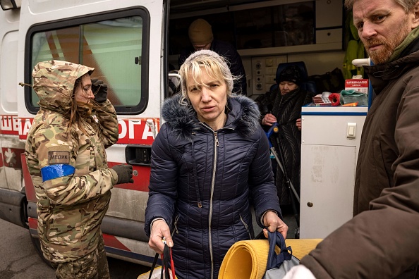 Une femme est aidée à sortir d'une ambulance après avoir fui son domicile dans la banlieue de Kiev à Stoyanka le 27 mars 2022. Photo de FADEL SENNA/AFP via Getty Images.