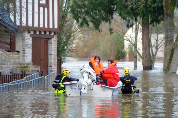 Rescuers evacuate people on February 9, 2014 in a flooded street in Malestroit, western France, after the Oust river overflowed. AFP PHOTO/FRED TANNEAU        (Photo credit should read FRED TANNEAU/AFP via Getty Images)