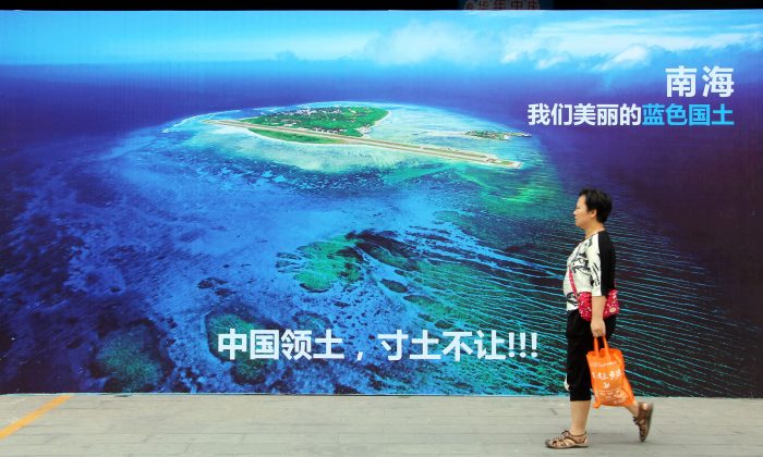 Une femme passe devant une affiche de la mer de Chine méridionale, avec le slogan en bas "Territoire de la Chine, ne jamais céder un pouce de notre sol", dans une rue de Weifang, dans la province chinoise du Shandong (est), le 14 juillet 2016. (STR/AFP/Getty Images)