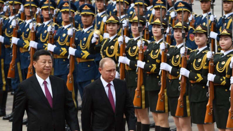 Le président russe Vladimir Poutine (au centre) passe en revue une garde d'honneur militaire avec le président chinois Xi Jinping (à gauche) lors d'une cérémonie de bienvenue devant le Grand Hall du Peuple à Pékin, le 8 juin 2018. (Greg Baker/POOL/AFP via Getty Images)