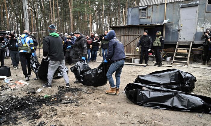 Des employés municipaux transportent des sacs mortuaires contenant six corps partiellement brûlés découverts dans la ville de Boutcha, en Ukraine, le 5 avril 2022. (Genya Savilov/AFP via Getty Images)