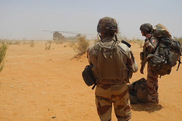 Deux soldats français attendent d'embarquer à bord d'un hélicoptère Chinook britannique à proximité de la base militaire française de Gossi, dans le centre du Mali, mars 2019.       (Photo : DAPHNE BENOIT/AFP via Getty Images)