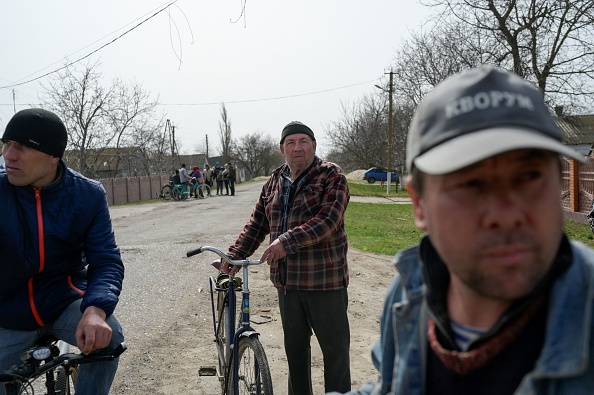 -Les gens se rassemblent dans le village déserté de Zelenyi Hai, dans le sud de l'Ukraine, entre Kherson et Mykolaïv, à moins de 5 km de la ligne de front le 1er avril 2022. Photo BULENT KILIC/AFP via Getty Images.