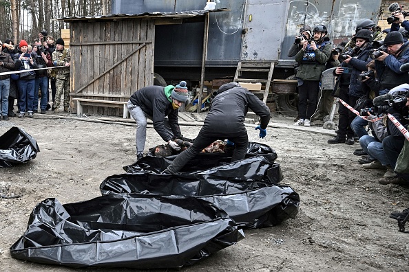 -Des policiers et des employés de la ville transportent six corps partiellement brûlés dans des sacs mortuaires dans la ville de Bucha le 5 avril 2022, Photo  Genya SAVILOV/AFP via Getty Images.