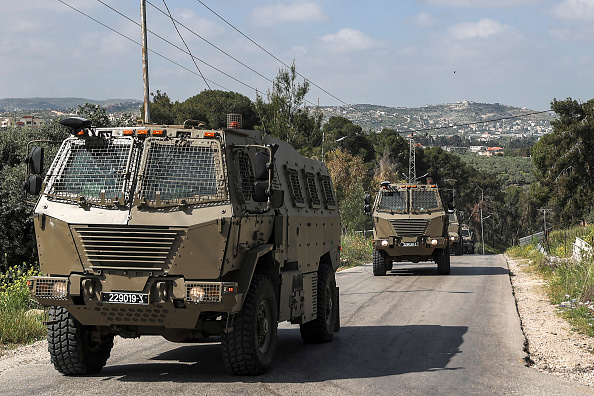 -Des véhicules militaires israéliens circulent lors d'affrontements entre Palestiniens et forces israéliennes dans le camp de réfugiés palestiniens de Jénine en Cisjordanie le 9 avril 2022. Photo de JAAFAR ASHTIYEH/AFP via Getty Images.