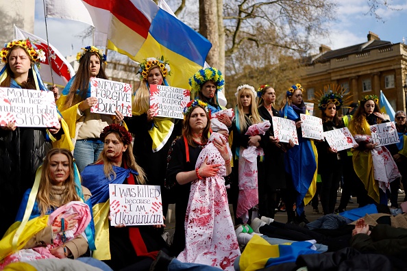 Des gens tiennent des pancartes, des drapeaux nationaux ukrainiens et des faux bébés éclaboussés de sang lors d'une manifestation en faveur de l'Ukraine dans le centre de Londres, le 9 avril 2022. Photo de TOLGA AKMEN/AFP via Getty Images.
