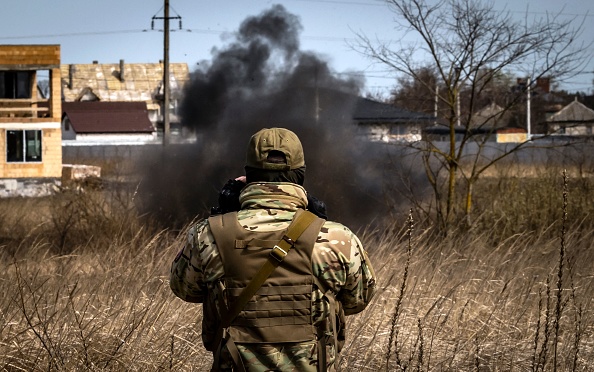Un membre d'une équipe de déminage regarde la fumée dans un champ de mines près de Brovary, au nord-est de Kiev, le 14 avril 2022, Photo de FADEL SENNA/AFP via Getty Images.