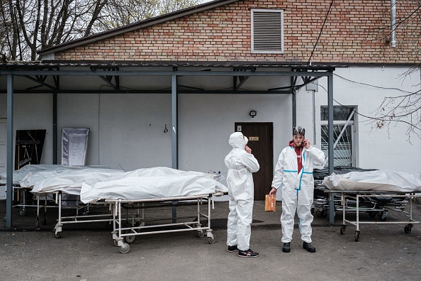 Des travailleurs font une pause à côté de sacs mortuaires alors qu'ils examinent les corps des victimes dans une morgue à Bucha, le 19 avril 2022, Ukraine. Photo de YASUYOSHI CHIBA/AFP via Getty Images.
