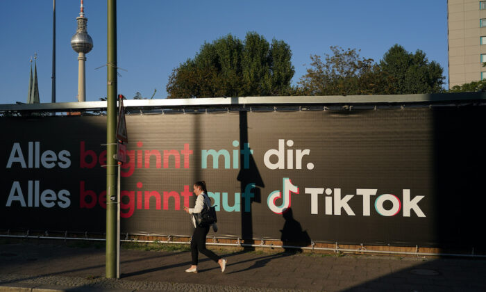 Une adolescente avec un smartphone passe devant une publicité pour TikTok, le 21 septembre 2020 à Berlin, en Allemagne. (Photo par Sean Gallup/Getty Images)