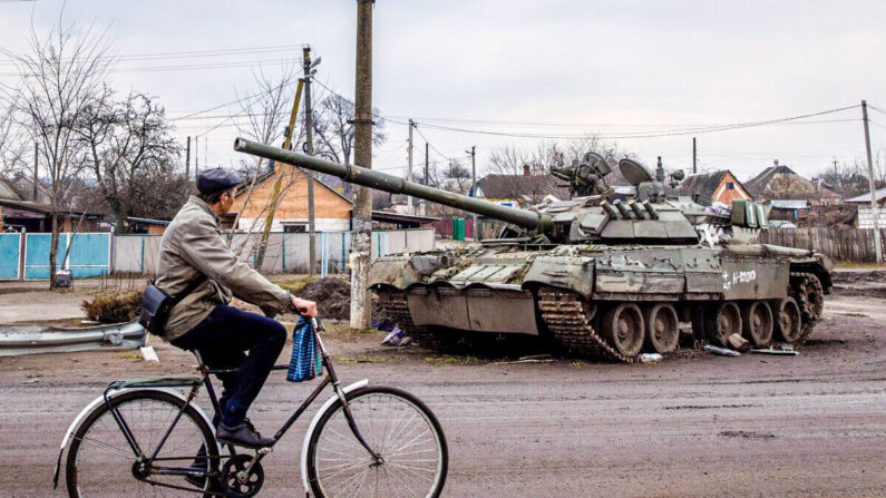 Un homme passe à vélo devant un char russe détruit à Trostianets, en Ukraine, le 30 mars 2022. (Chris McGrath/Getty Images)