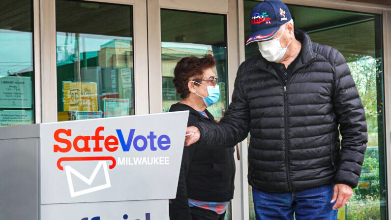 Des habitants placent des bulletins de vote par correspondance dans une urne à l'extérieur de la Tippecanoe branch library à Milwaukee, le 20 octobre 2020. (Scott Olson/Getty Images)