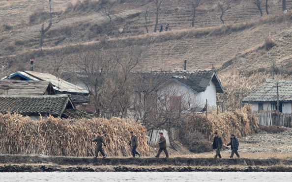 -Illustration- Des hommes nord-coréens marchent au milieu d'un paysage sec et aride sur les rives de la rivière Yalu, à environ 70 km au nord de Dandong. Photo FREDERIC J. BROWN/AFP via Getty Images.