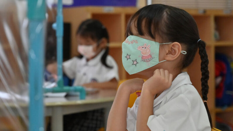 Une fillette joue avec son masque facial en classe, à Bangkok, Thaïlande, le 17 juin 2020 (Photo par ROMEO GACAD/AFP via Getty Images)