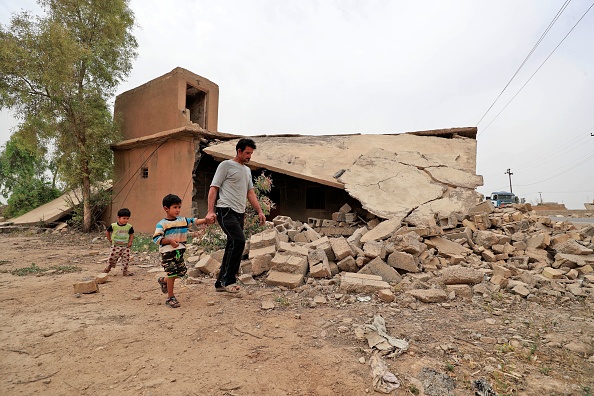-Issa al-Zamzoum, père de cinq enfants irakiens, passe devant une maison détruite dans le village ravagé par la guerre, à environ 180 kilomètres au nord de la capitale irakienne Bagdad, le 25 avril 2022. Photo par AHMAD AL-RUBAYE/AFP via Getty Images.