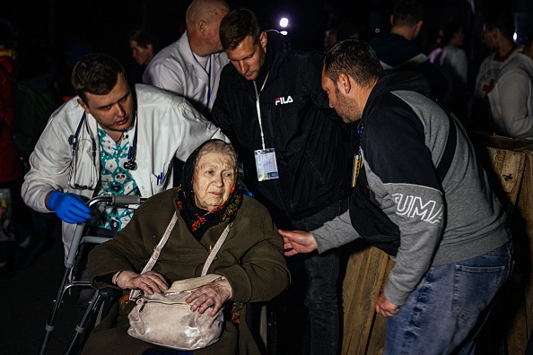 Une femme âgée évacuée de Marioupol est poussée sur un fauteuil roulant dans une zone d'enregistrement et de traitement des personnes déplacées à Zaporizhzhia, le 8 mai 2022. Photo de Dimitar DILKOFF / AFP via Getty Images.