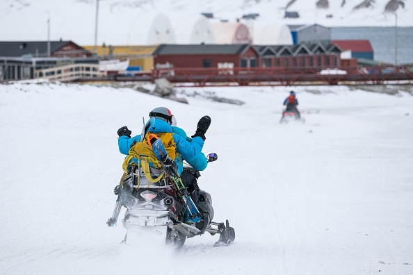 -Des gens conduisent leur motoneige à Longyearbyen, le 9 mai 2022, sur l'île du Spitzberg, dans l'archipel du Svalbard, au nord de la Norvège. Photo de Jonathan NACKSTRAND / AFP via Getty Images.