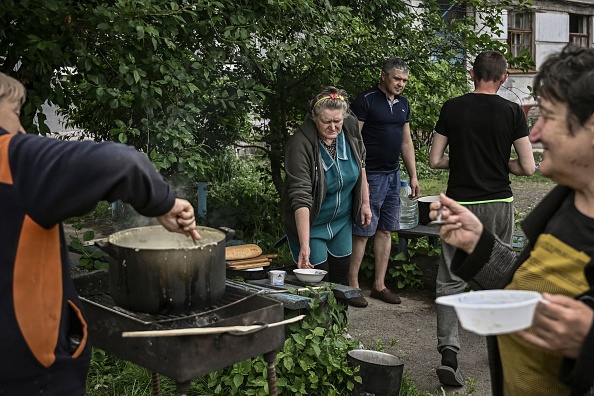 Les habitants de la ville de Lysychansk cuisinent à l'extérieur de leurs maisons, car la ville est sans électricité ni eau, dans la région ukrainienne orientale du Donbass, le 26 mai 2022. Photo par ARIS MESSINIS/AFP via Getty Images.