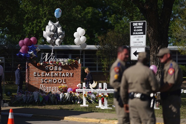 -Des policiers se tiennent à côté d'un mémorial de fortune à l'extérieur de la Robb Elementary School le 26 mai 2022 à Uvalde, au Texas. Photo par ALLISON DINNER/AFP via Getty Images.