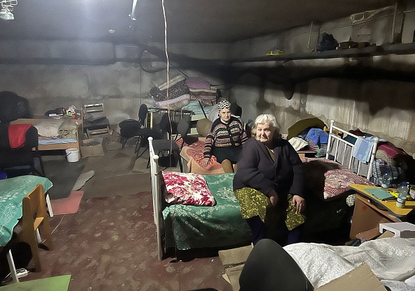Des femmes âgées sont assises sur des lits dans un sous-sol, alors qu'elles se cachent des bombardements, dans le village de Kutuzivka, région de Kharkiv, le 27 mai 2022, Photo de PATRICK FORT/AFP via Getty Images.