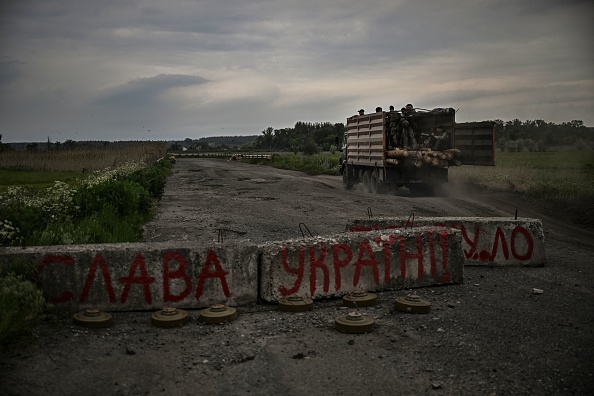 Un camion avec des militaires ukrainiens passe devant un barrage routier, portant l'inscription Gloire à l'Ukraine dans la région ukrainienne orientale du Donbass, le 29 mai 2022. Photo par ARIS MESSINIS/AFP via Getty Images.
