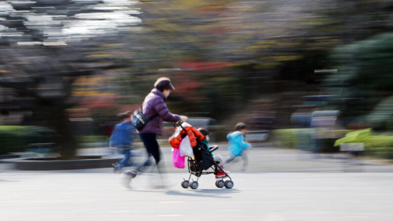 Une femme se promène avec une poussette et des enfants dans un parc à Tokyo. (Yoshikazu Tsuno/AFP via Getty Images)
