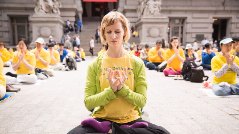 Une pratiquante de Falun Gong médite avec d'autres personnes près de Battery Park à Manhattan lors de la Journée mondiale du Falun Dafa, le 13 mai 2015. (Laura Cooksey)