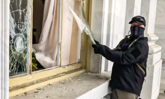 Manifestant suspect en train de vandaliser une fenêtre du Capitole le 6 janvier 2021. L’individu n'a pas été placé sur la liste des personnes recherchées par le FBI, ni arrêté ou inculpé. (Bobby Powell/Capture d’écran Epoch Times)