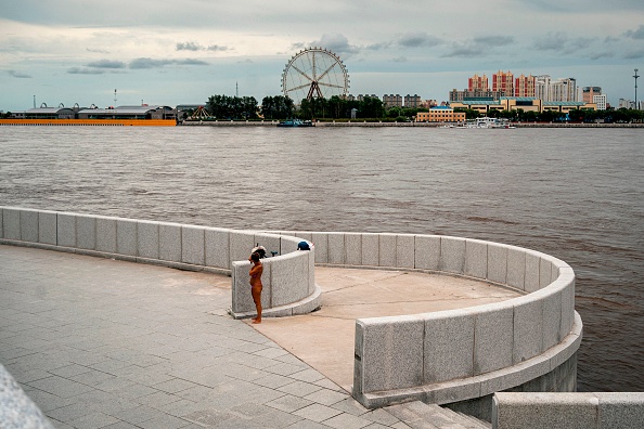 -Une berge du fleuve Amour, avec la ville chinoise de Heihe vue en arrière-plan, dans la ville de l'extrême-est russe de Blagovechtchensk, la Russie et la Chine ont inauguré le 10 juin 2022 le premier pont routier entre les deux pays. Photo de DIMITAR DILKOFF /AFP via Getty Images.