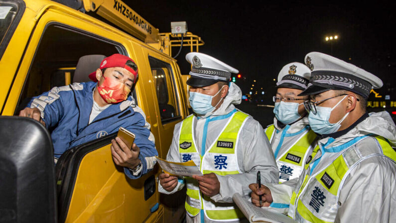 Policiers vérifiant les informations d'un chauffeur de camion à un poste de contrôle à Ningbo, dans la province du Zhejiang, en Chine, le 18 décembre 2021. (STR/AFP via Getty Images)