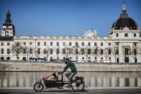 Un homme fait du vélo-cargo avec ses enfants, le 23 mars 2022 à Lyon.  (JEFF PACHOUD/AFP via Getty Images)