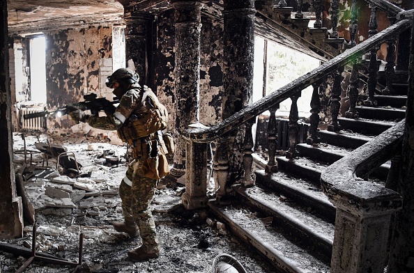 -Un soldat russe patrouille au théâtre dramatique de Marioupol, bombardé le 16 mars dernier, le 12 avril 2022 à Marioupol. Photo par Alexander NEMENOV / AFP via Getty Images.