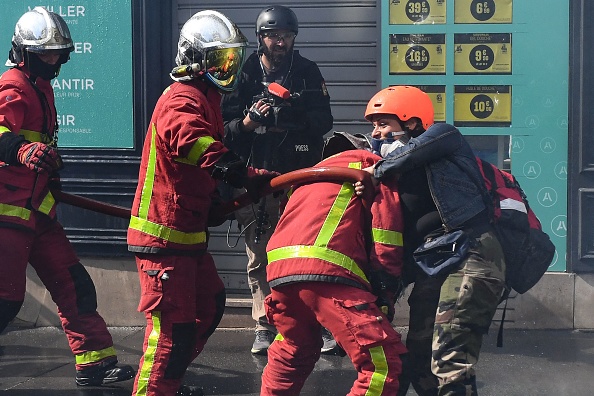 Une "street médic" tente d'empêcher un pompier d'éteindre un incendie au milieu d'affrontements en marge du rassemblement du 1er mai 2022 à Paris.  (Photo : ALAIN JOCARD/AFP via Getty Images)