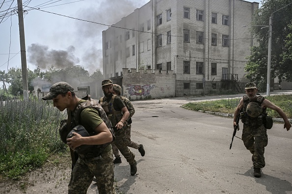 -Des militaires ukrainiens courent pour se mettre à l'abri lors d'un duel d'artillerie entre les troupes ukrainiennes et russes dans la ville de Lysychansk, dans la région ukrainienne du Donbass, le 11 juin 2022. Photo par ARIS MESSINIS / AFP via Getty Images.