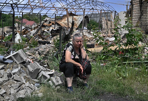 Kateryna, 70 ans, attend avec d'autres résidents locaux une aide humanitaire à côté d'une maison détruite le long d'une rue de la ville de Bucha, le 16 juin 2022, Photo Genya SAVILOV/AFP via Getty Images.