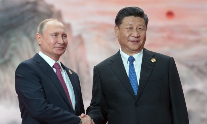 Le président russe Vladimir Poutine serre la main du dirigeant chinois Xi Jinping lors d'une cérémonie de bienvenue au sommet des chefs d'État de l'Organisation de coopération de Shanghai tenu à Qingdao, en Chine, le 10 juin 2018. (Sergei Guneyev/Sputnik/AFP via Getty Images)