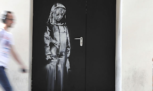 "La Jeune fille triste" peinte au pochoir par l'artiste de rue Banksy à Paris, le 25 juin 2018, dans une rue latérale à la salle de concert  du Bataclan où une attaque terroriste a tué 90 personnes le 13 novembre 2015.        (Photo : THOMAS SAMSON/AFP via Getty Images)