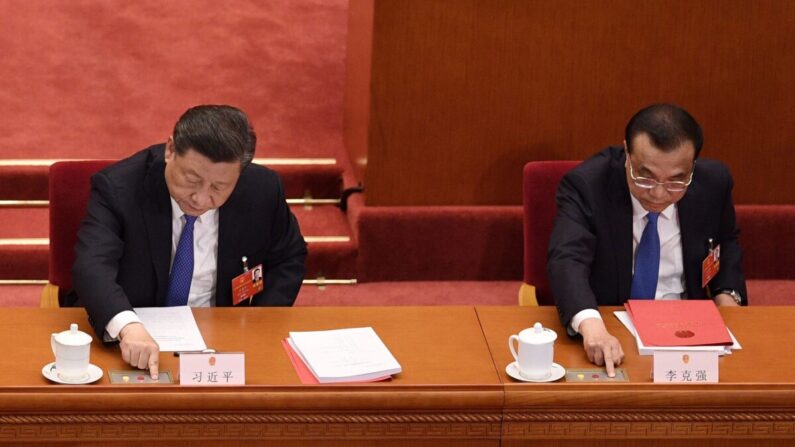 Le dirigeant chinois Xi Jinping (à g.) et le Premier ministre Li Keqiang en plein vote lors de la séance de clôture de la réunion annuelle de l'assemblée législative, à Pékin, en Chine, le 28 mai 2020. (NICOLAS ASFOURI/AFP via Getty Images)