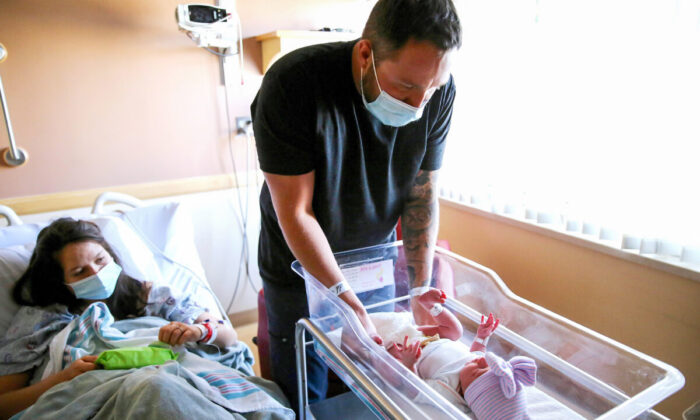 Un père se prépare à changer la couche de sa fille sous le regard de sa femme dans un hôpital d'Apple Valley, en Californie, le 30 mars 2021. (Mario Tama/Getty Images)