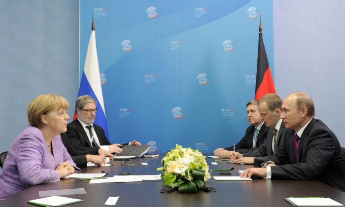 La chancelière allemande Angela Merkel et le président russe Vladimir Poutine s'entretiennent lors de leur réunion tenue dans le cadre du Forum économique international à Saint-Pétersbourg, en Russie, le 21 juin 2013. (Mikhail Klimentyev/AFP/Getty Images)