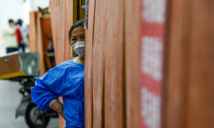 Femme bénévole derrière la clôture d'une zone résidentielle sous confinement dans le quartier de Huangpu, à Shanghai, le 22 juin 2022. (Liu Jin/AFP via Getty Images)