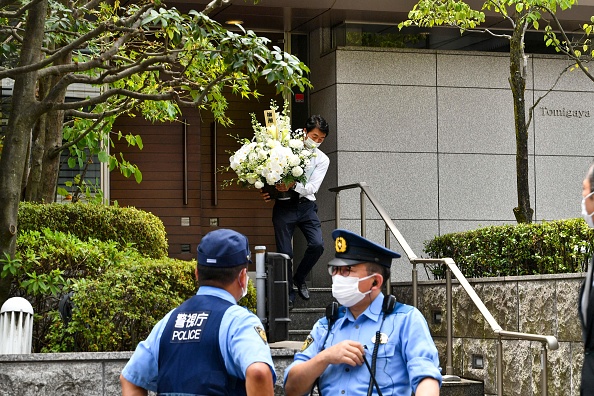 -Un homme porte des fleurs à la résidence de l'ancien Premier ministre japonais Shinzo Abe décédé, à Tokyo le 9 juillet 2022. Photo de KAZUHIRO NOGI/AFP via Getty Images.