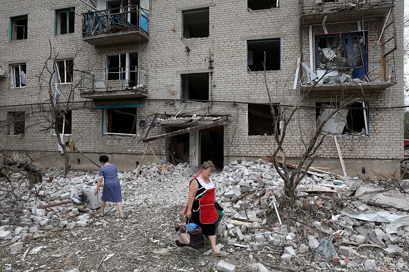 -Une résidente locale transporte ses affaires hors d'un bâtiment partiellement détruit à Chasiv Yar, dans l'est de l'Ukraine, le 10 juillet 2022. Photo par ANATOLII STEPANOV/AFP via Getty Images.