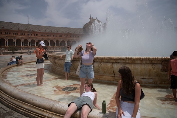 Les gens se rafraîchissent avec l'eau d'une fontaine lors d'une vague de chaleur à Séville le 12 juillet 2022. Photo de JORGE GUERRERO/AFP via Getty Images.
