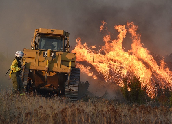 Des pompiers utilisent un bulldozer alors qu'ils éteignent un incendie dans le village de Tabara, près de Zamora, dans le nord-ouest de l'Espagne, le 18 juillet 2022. (MIGUEL RIOPA/AFP via Getty Images)