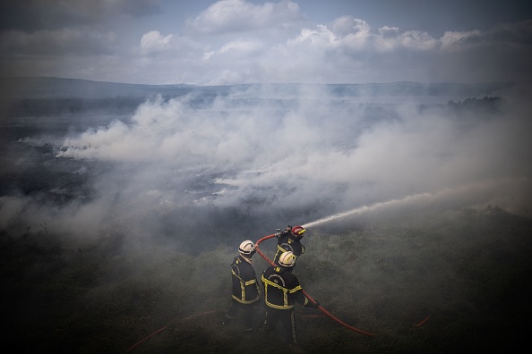 Des pompiers pulvérisent de l'eau sur un feu de forêt dans les Monts d'Arrée, près de Brasparts, en Bretagne, le 19 juillet 2022. (Photo : LOIC VENANCE/AFP via Getty Images)