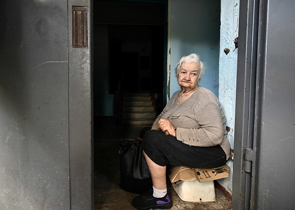 -Galyna Chorna, 75 ans, assise dans l'entrée d'un immeuble endommagé de neuf étages où elle vit à Kharkiv, le 29 juillet 2022. Photo by Genya SAVILOV/AFP via Getty Images.