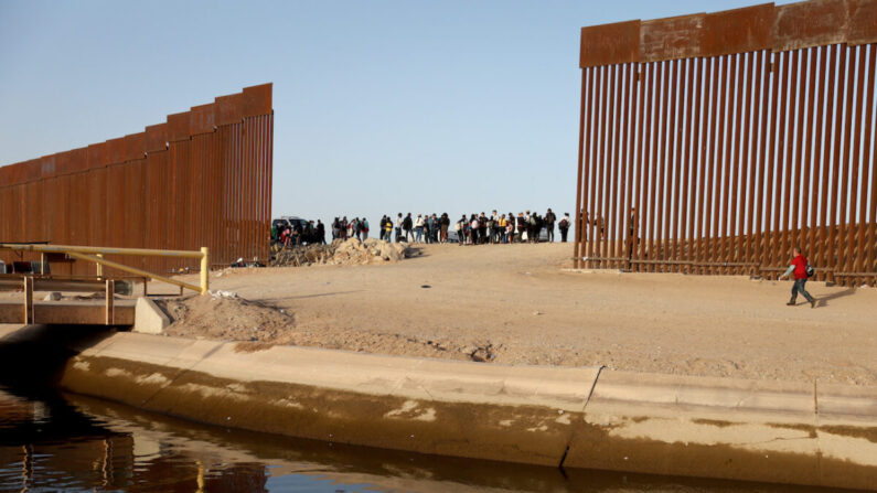 Immigrés clandestins au niveau d'une brèche de la barrière frontalière entre les États-Unis et le Mexique. Ils attendent qu’une patrouille frontalière américaine vienne les prendre en charge, à Yuma, en Arizona, le 20 mai 2022. (Mario Tama/Getty Images)
